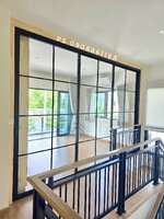 กั้นห้องหน้าบันไดด้วยประตูบานเลื่อนอลูมิเนียมสีดำกระจกใสคาดลายลูกฟักทำเป็นห้องเพื่อติดแอร์